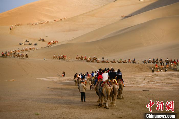 图为游客骑骆驼畅游鸣沙山。　王斌银 摄